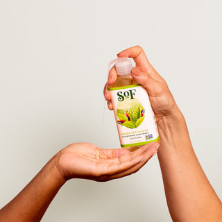 A person dispenses Green Tea Leaves Nourishing Hand Wash into another person's cupped palm against a plain light background.